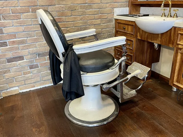 A white barber chair in front of a brick wall